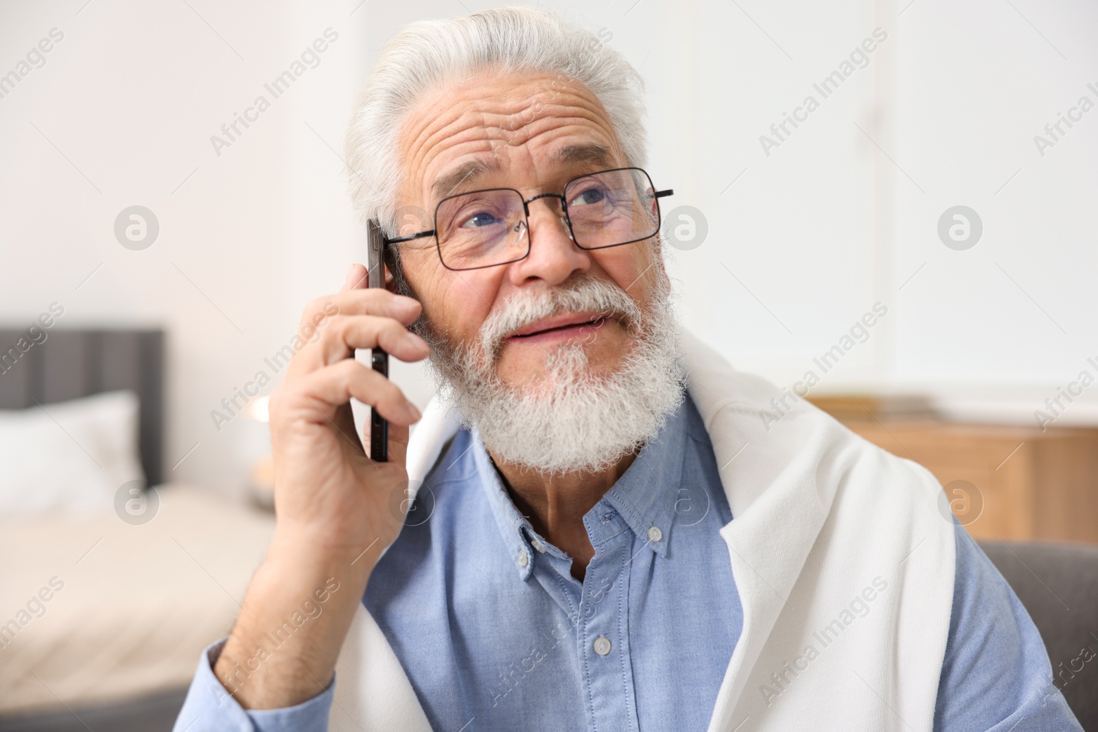 Photo of Handsome bearded man talking on smartphone indoors