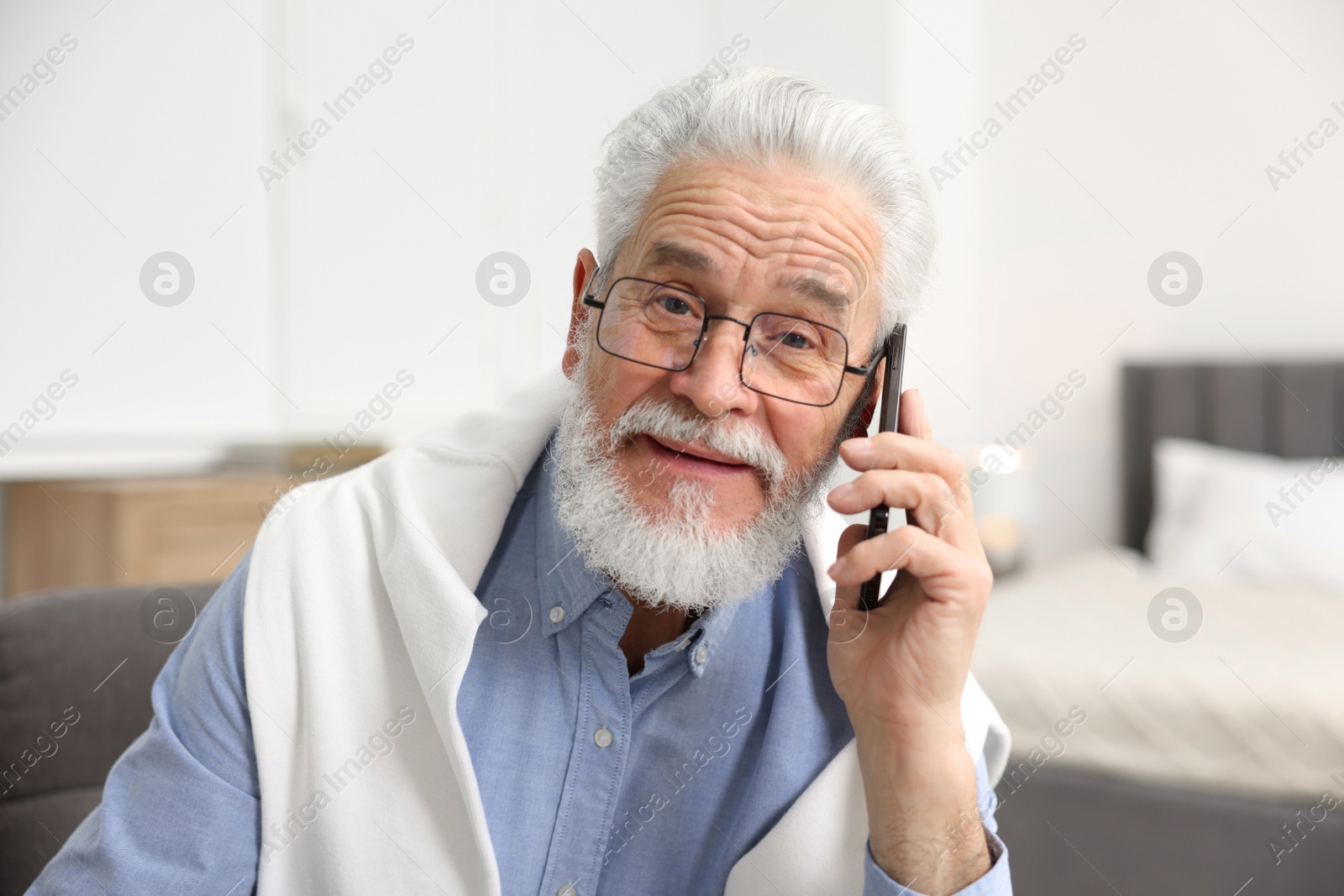 Photo of Handsome bearded man talking on smartphone indoors