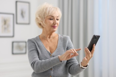 Photo of Portrait of beautiful grandmother using smartphone at home