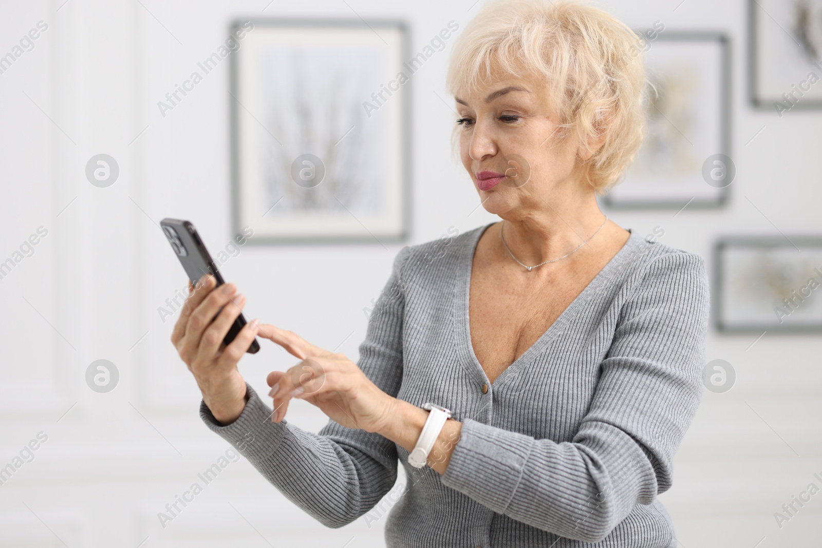 Photo of Portrait of beautiful grandmother using smartphone at home