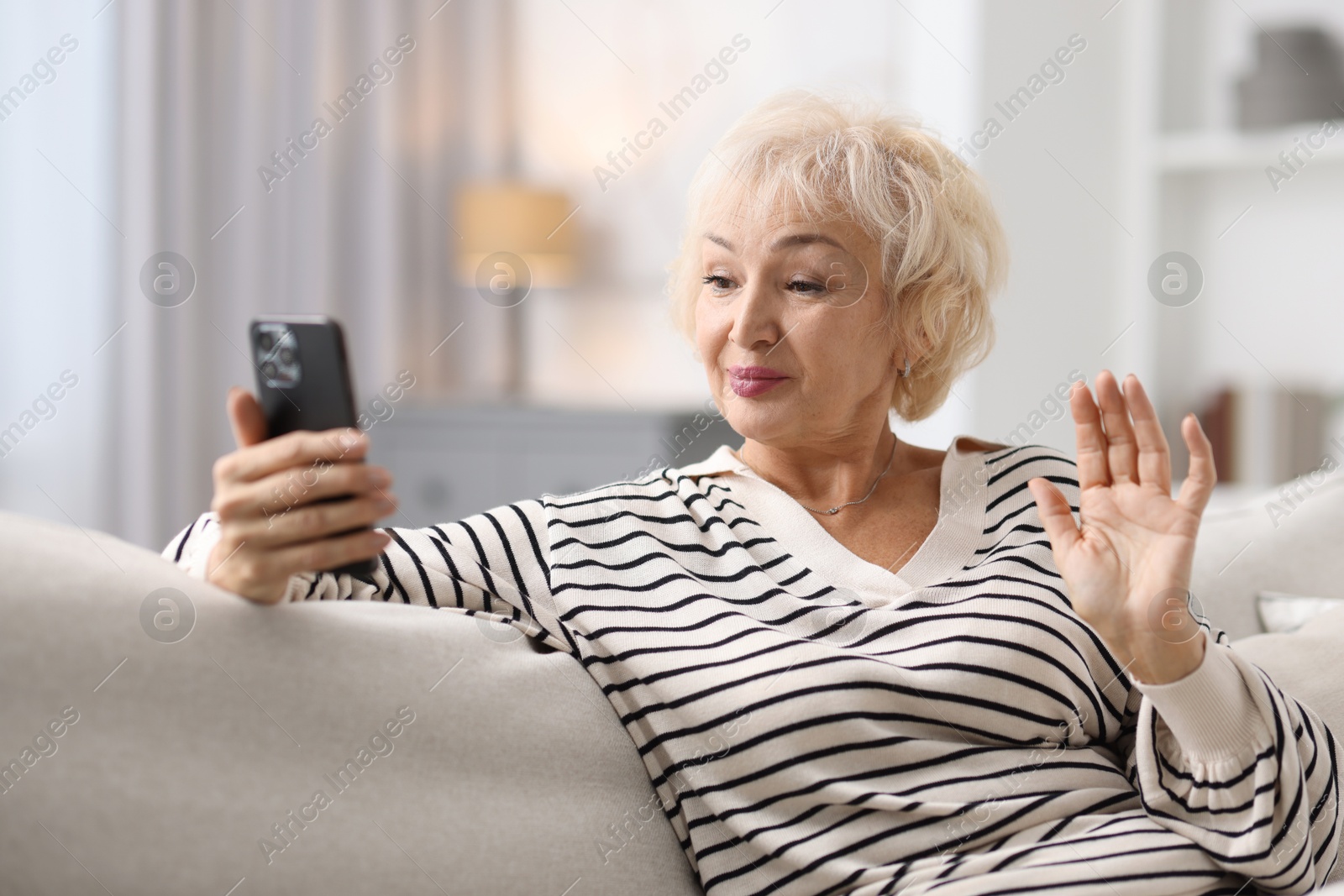 Photo of Beautiful grandmother having video chat via smartphone at home