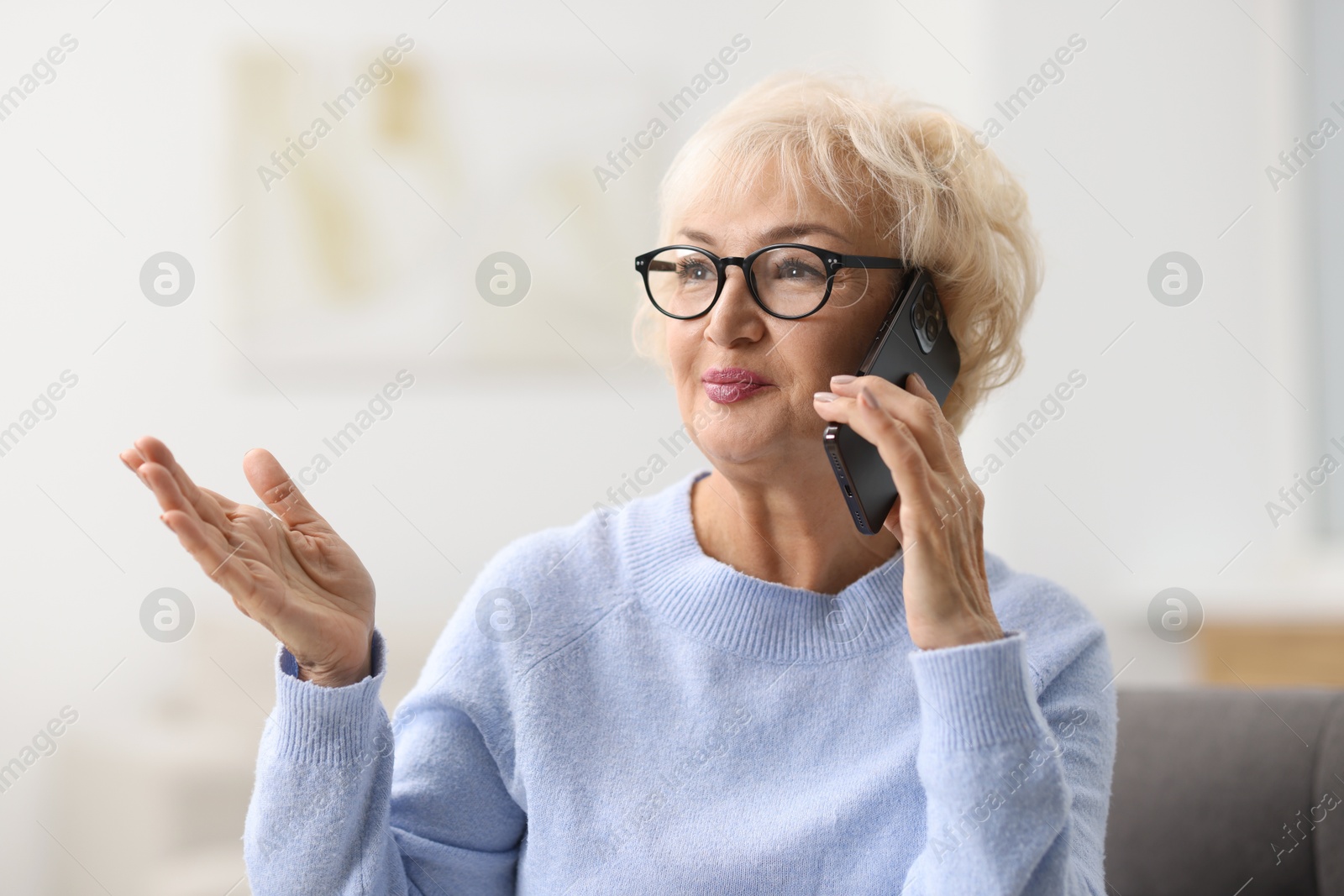 Photo of Beautiful grandmother talking on smartphone at home