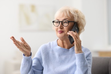 Photo of Beautiful grandmother talking on smartphone at home