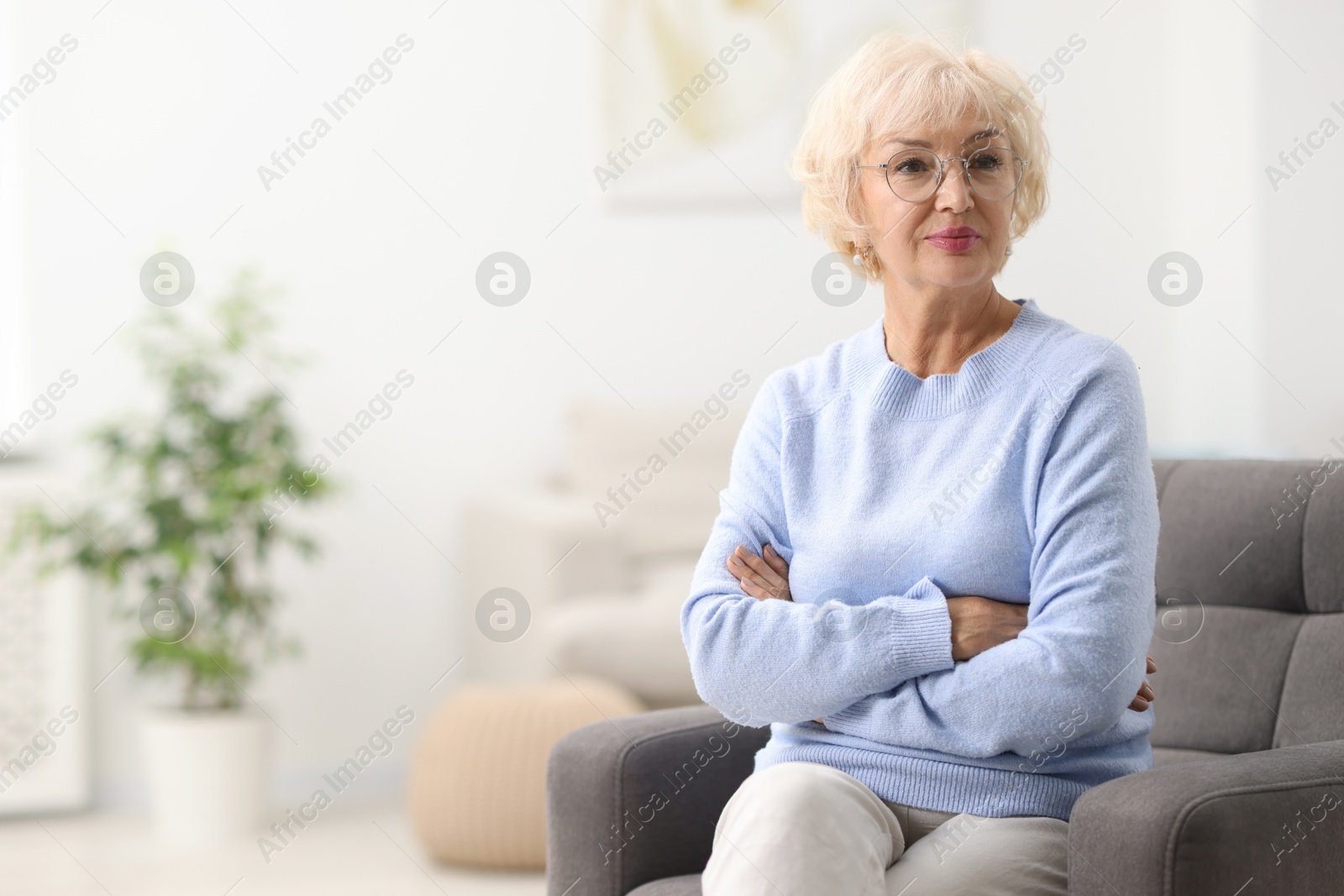 Photo of Beautiful grandmother sitting in armchair at home. Space for text