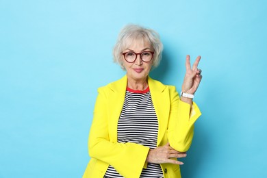 Photo of Portrait of fashionable grandmother in yellow jacket on light blue background