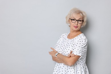 Portrait of elegant grandmother in glasses on light grey background. Space for text