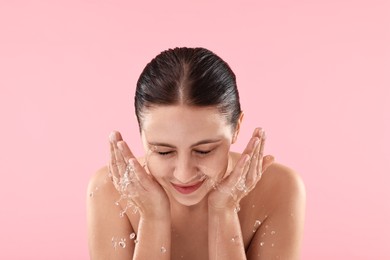 Photo of Attractive woman washing her face on pink background