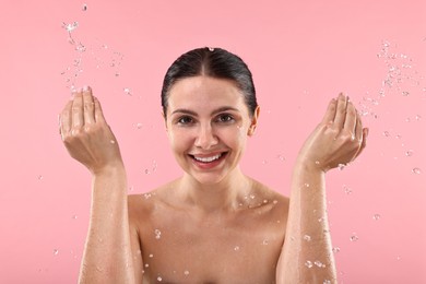 Photo of Smiling woman washing her face on pink background