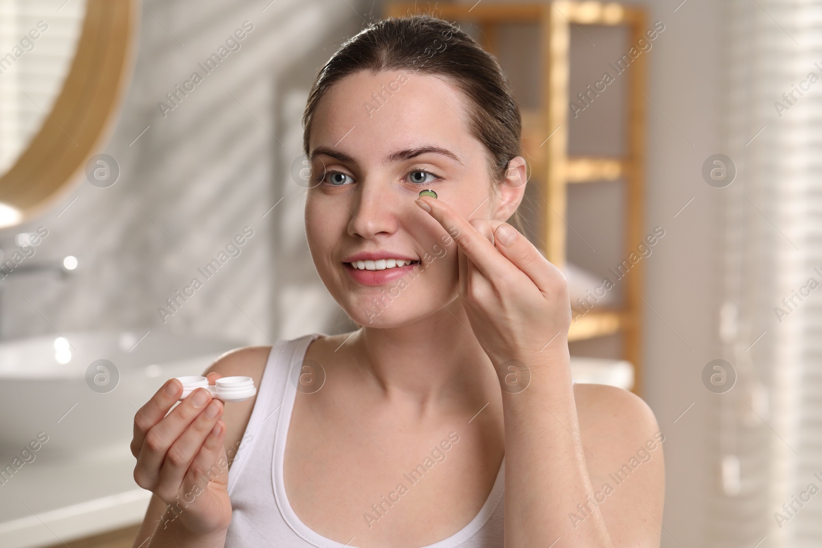 Photo of Young woman with green color contact lens indoors