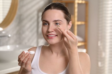 Photo of Young woman with green color contact lens indoors