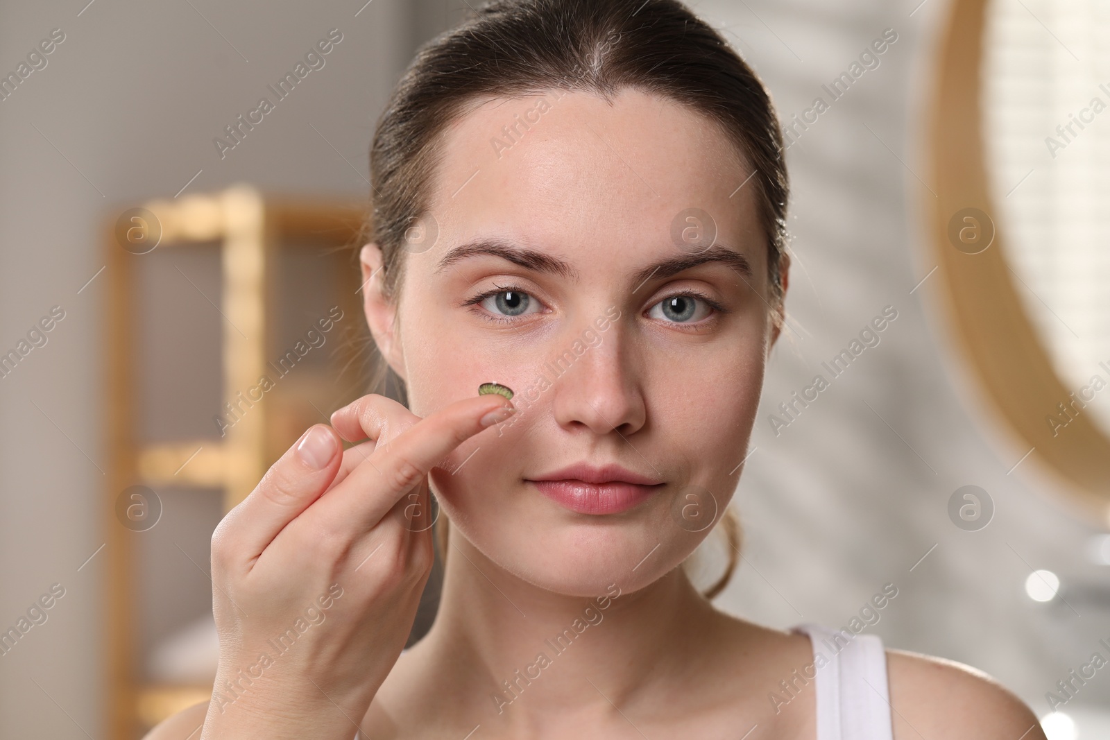 Photo of Young woman with green color contact lens indoors, closeup