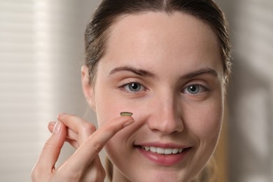 Photo of Young woman with green color contact lens indoors, closeup