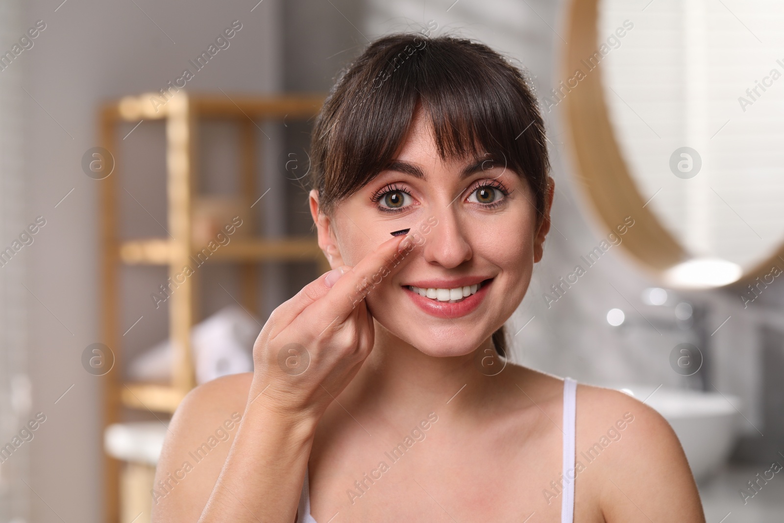 Photo of Young woman with color contact lens in bathroom