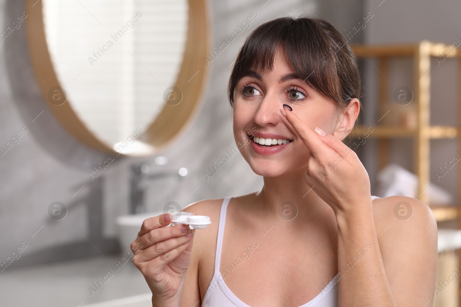 Photo of Young woman with color contact lens and case in bathroom. Space for text