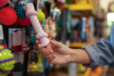 Photo of Woman choosing toy in pet shop, closeup