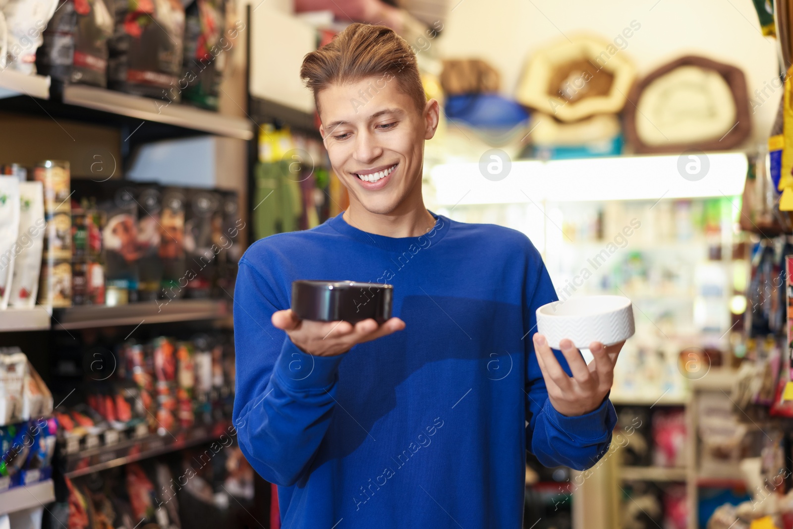 Photo of Happy man choosing feeding bowl in pet shop