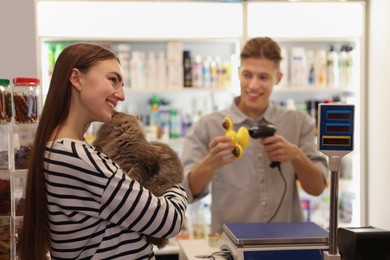 Photo of Woman buying toy for her cat in pet shop, selective focus