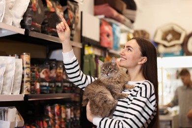 Woman with her cute cat in pet shop