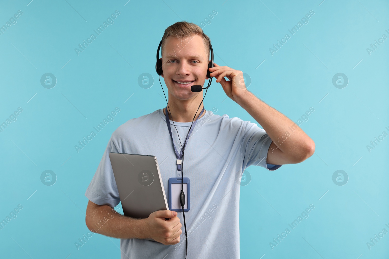 Photo of Technical support call center. Smiling operator with laptop on light blue background