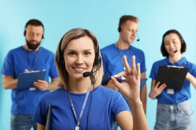 Photo of Technical support call center. Team of friendly operators on light blue background