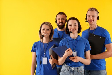 Photo of Technical support call center. Team of friendly operators on yellow background. Space for text