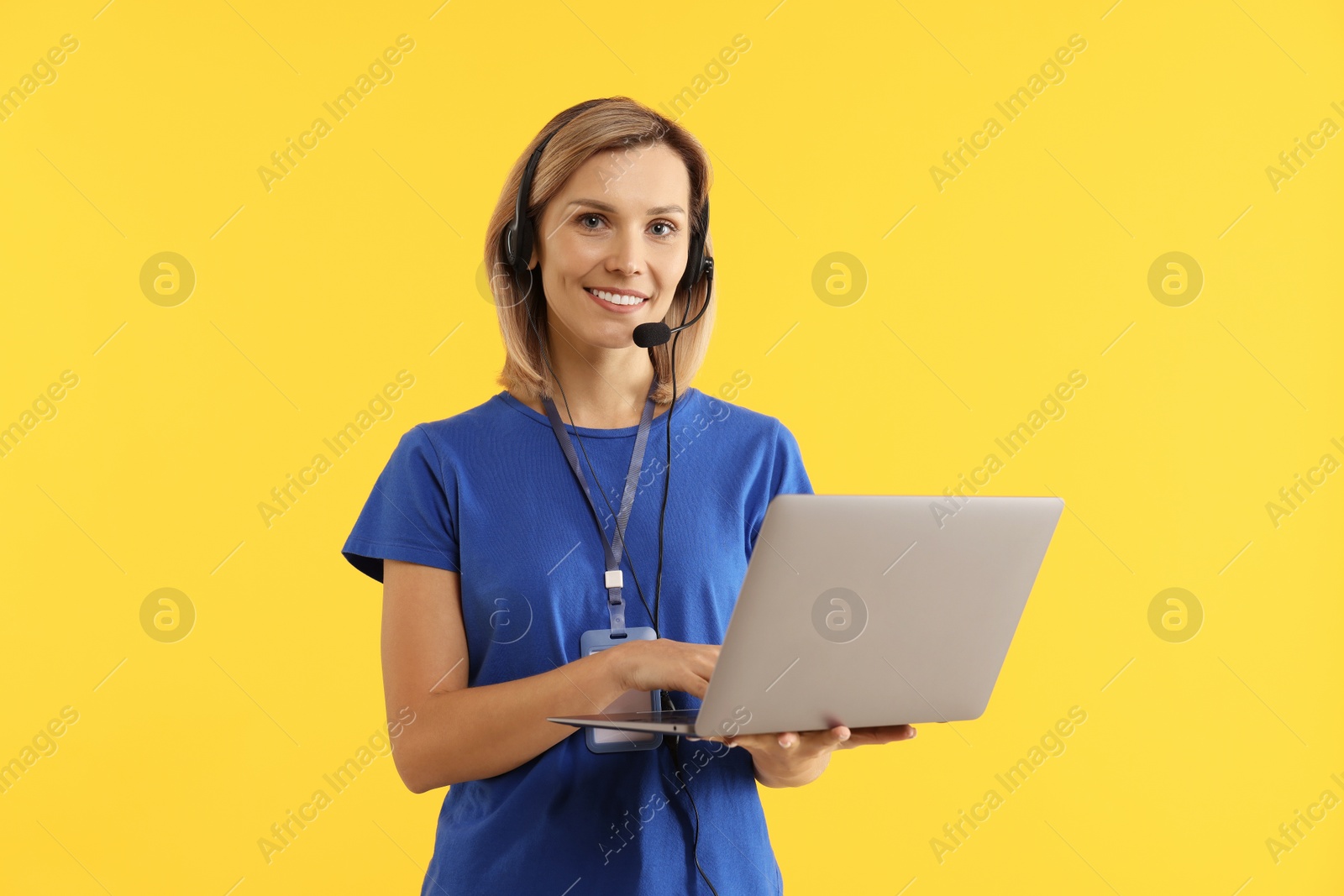 Photo of Technical support call center. Smiling operator with laptop on yellow background