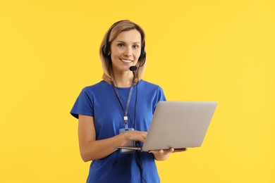 Photo of Technical support call center. Smiling operator with laptop on yellow background