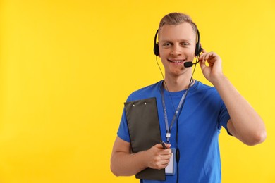 Photo of Technical support call center. Smiling operator with clipboard on yellow background. Space for text