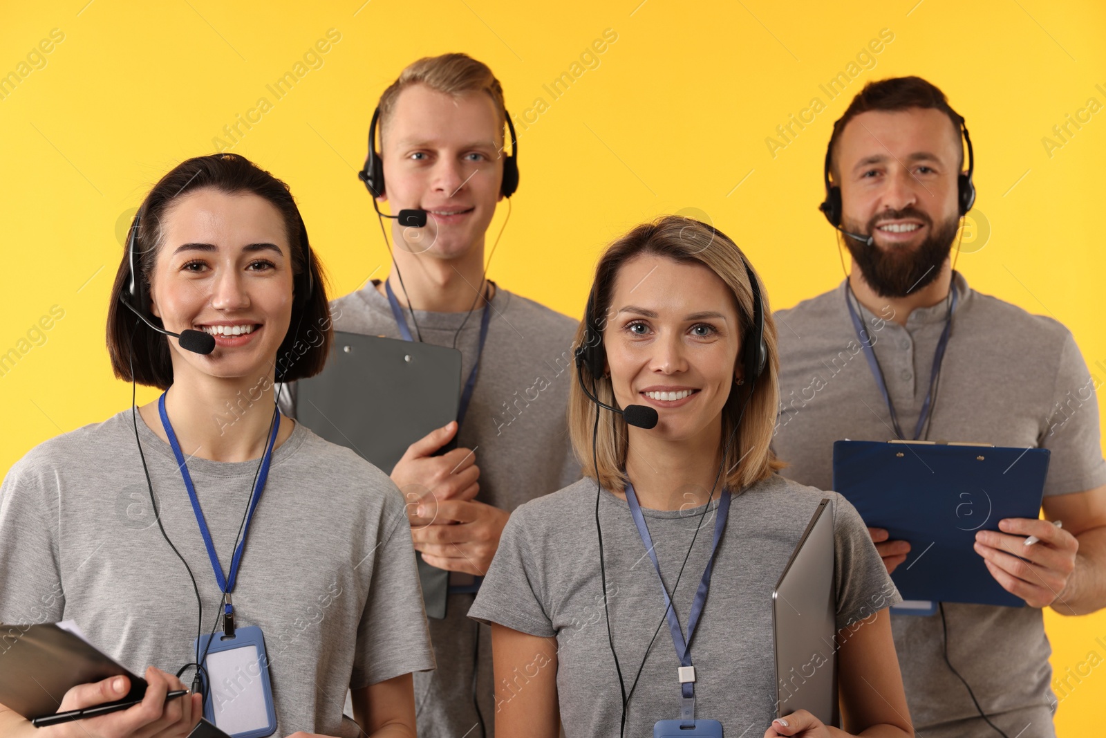 Photo of Technical support call center. Team of friendly operators on yellow background