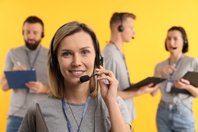 Photo of Technical support call center. Smiling operator on yellow background, selective focus