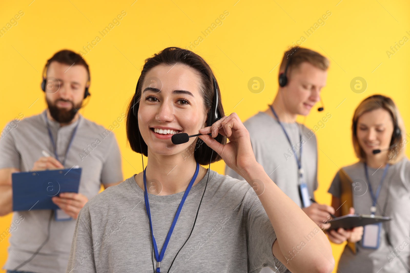 Photo of Technical support call center. Team of friendly operators on yellow background