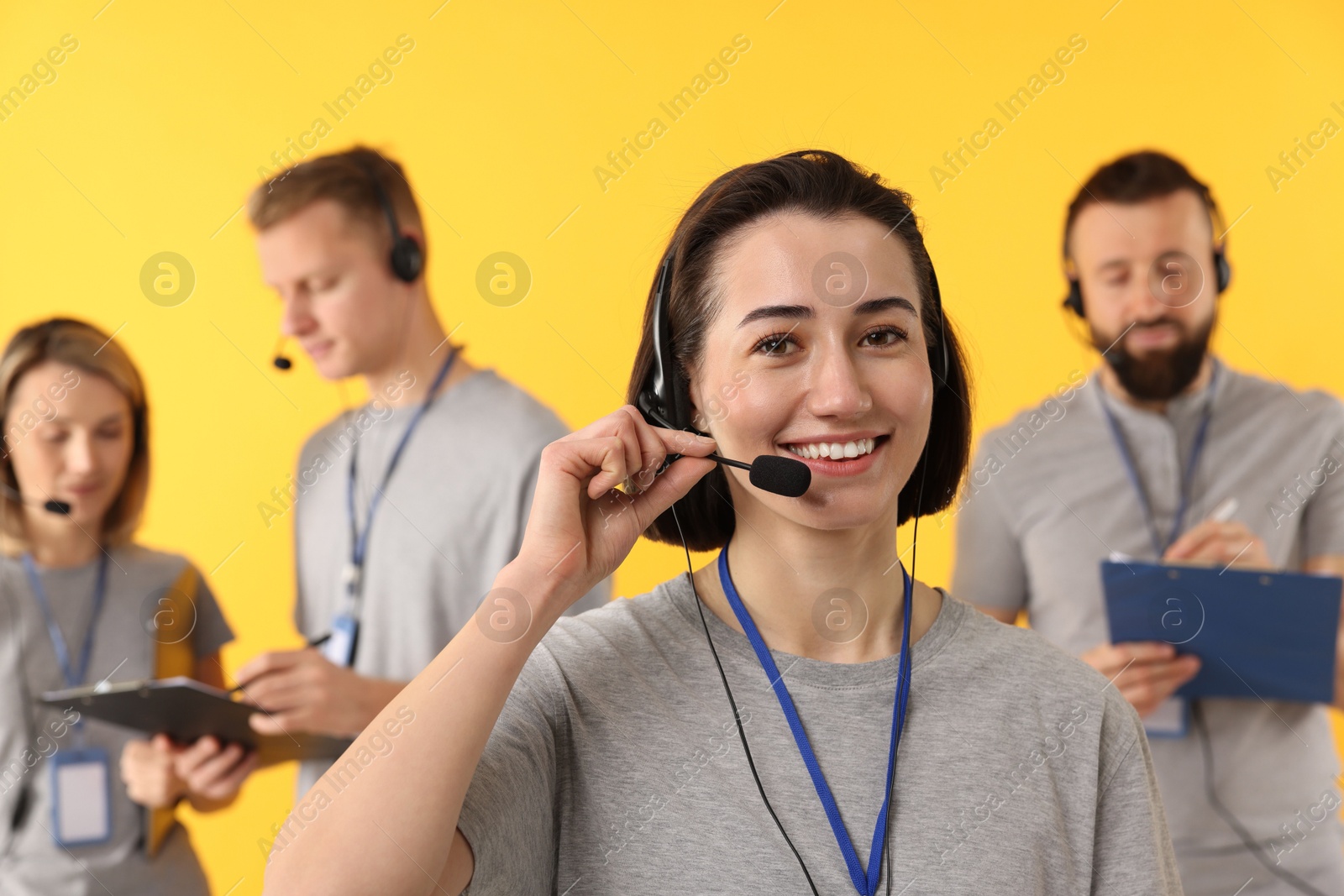 Photo of Technical support call center. Team of friendly operators on yellow background