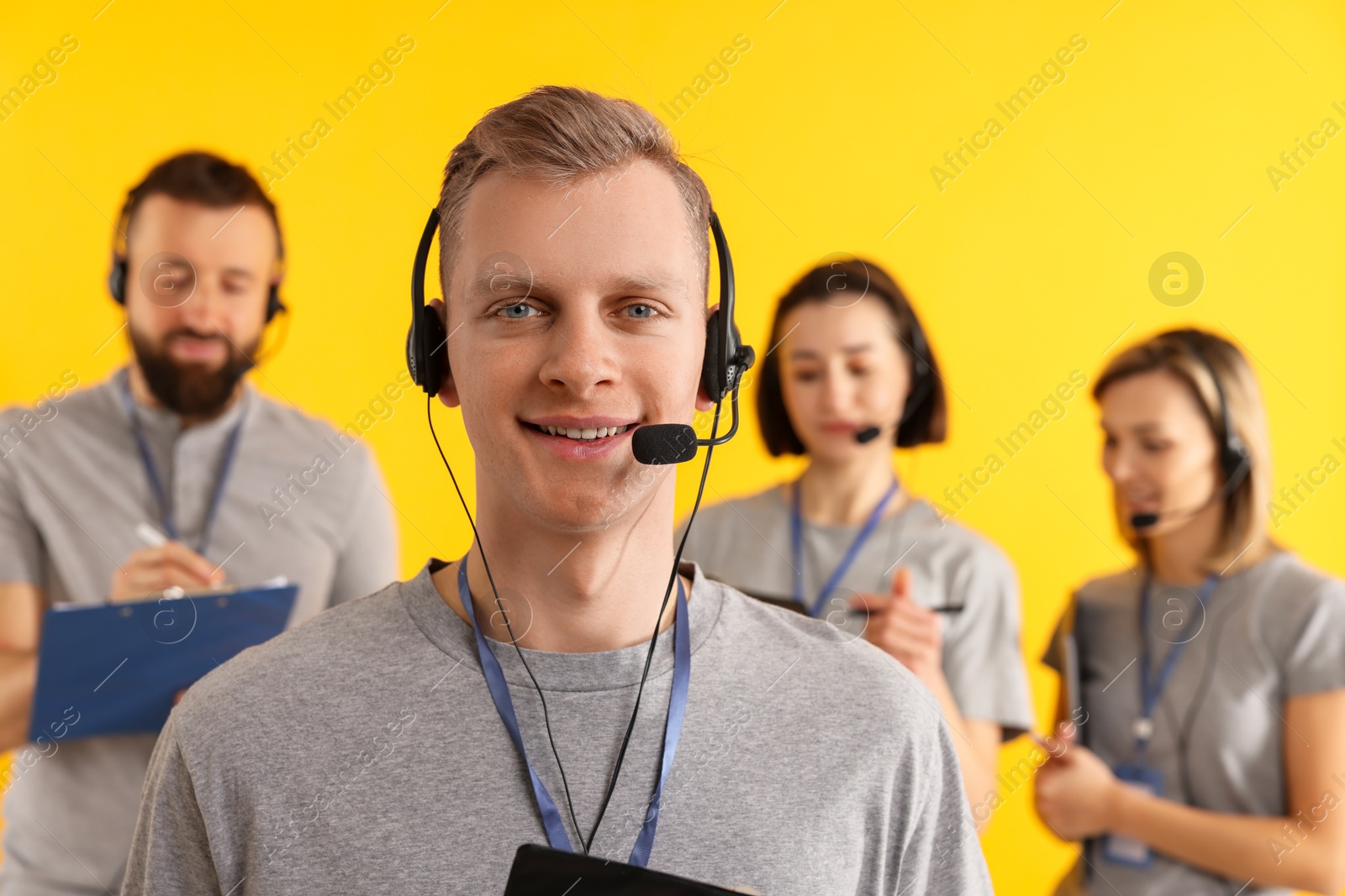 Photo of Technical support call center. Team of friendly operators on yellow background