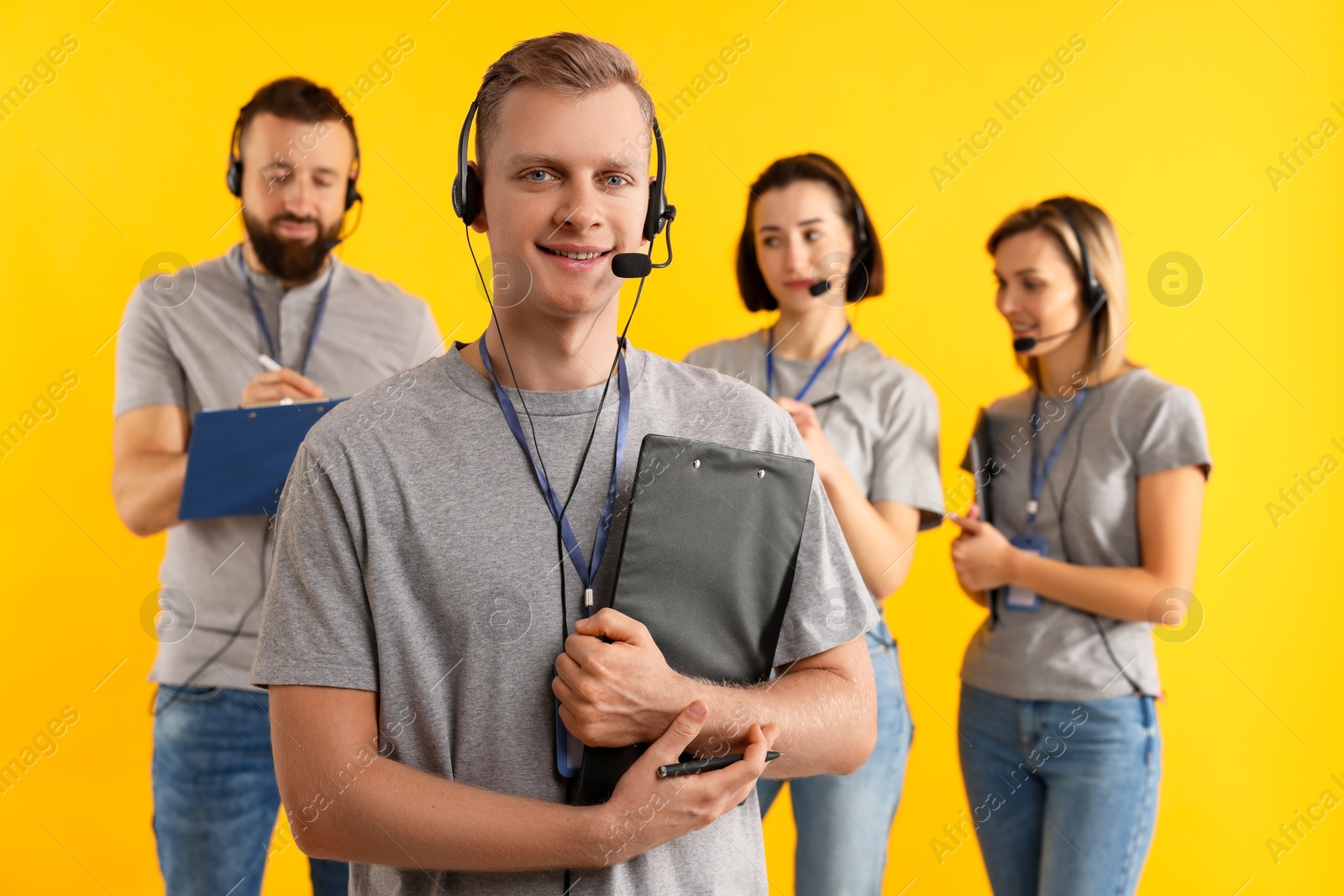 Photo of Technical support call center. Team of friendly operators on yellow background