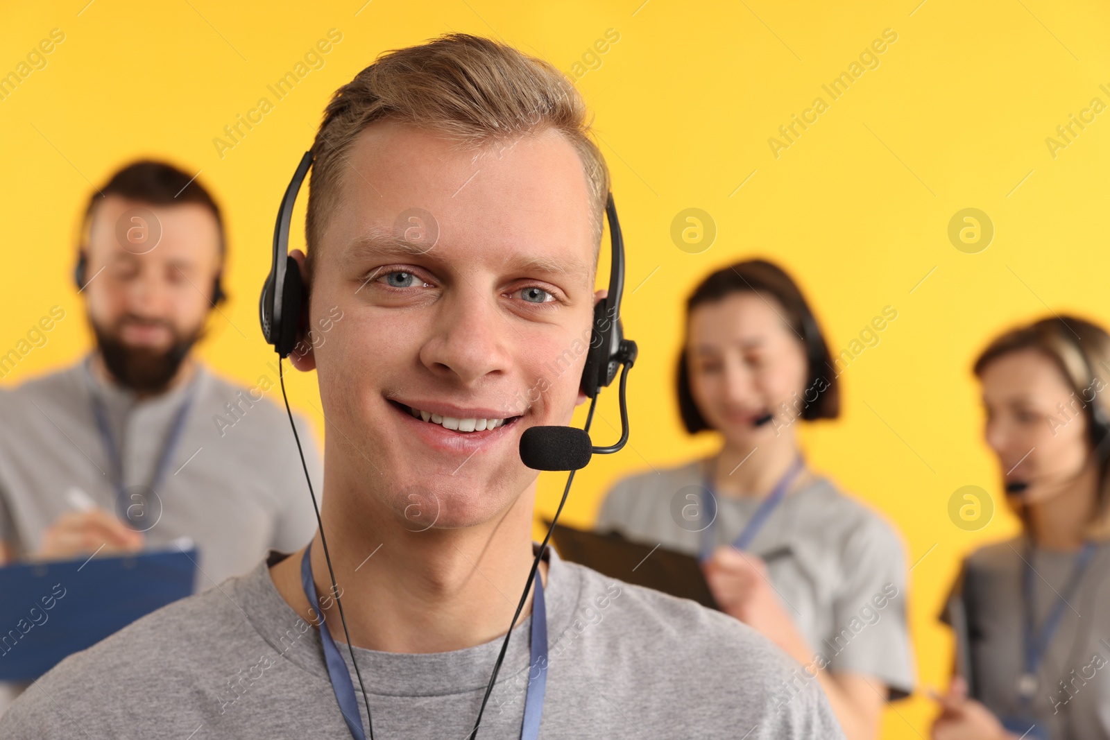 Photo of Technical support call center. Smiling operator on yellow background, selective focus