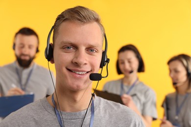 Technical support call center. Smiling operator on yellow background, selective focus