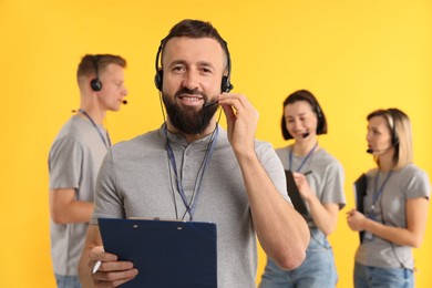 Photo of Technical support call center. Smiling operator on yellow background, selective focus