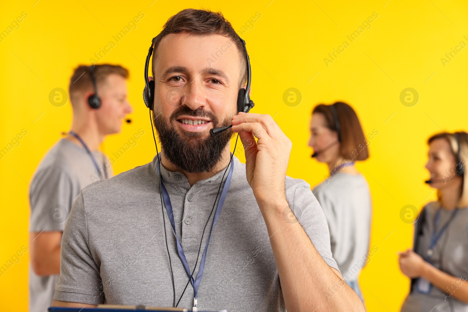 Photo of Technical support call center. Smiling operator on yellow background, selective focus