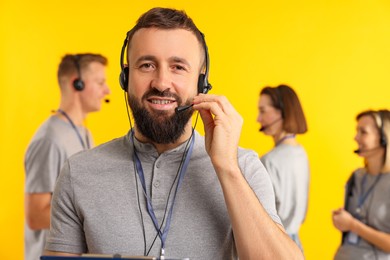 Photo of Technical support call center. Smiling operator on yellow background, selective focus