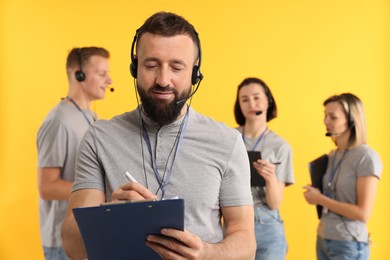 Photo of Technical support call center. Team of friendly operators on yellow background