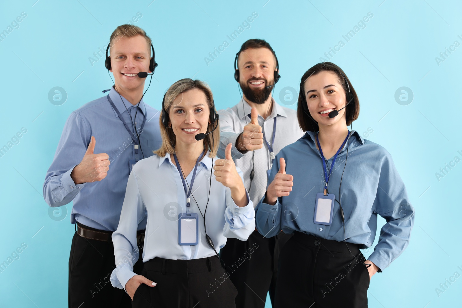 Photo of Technical support call center. Team of friendly operators showing thumbs up on light blue background