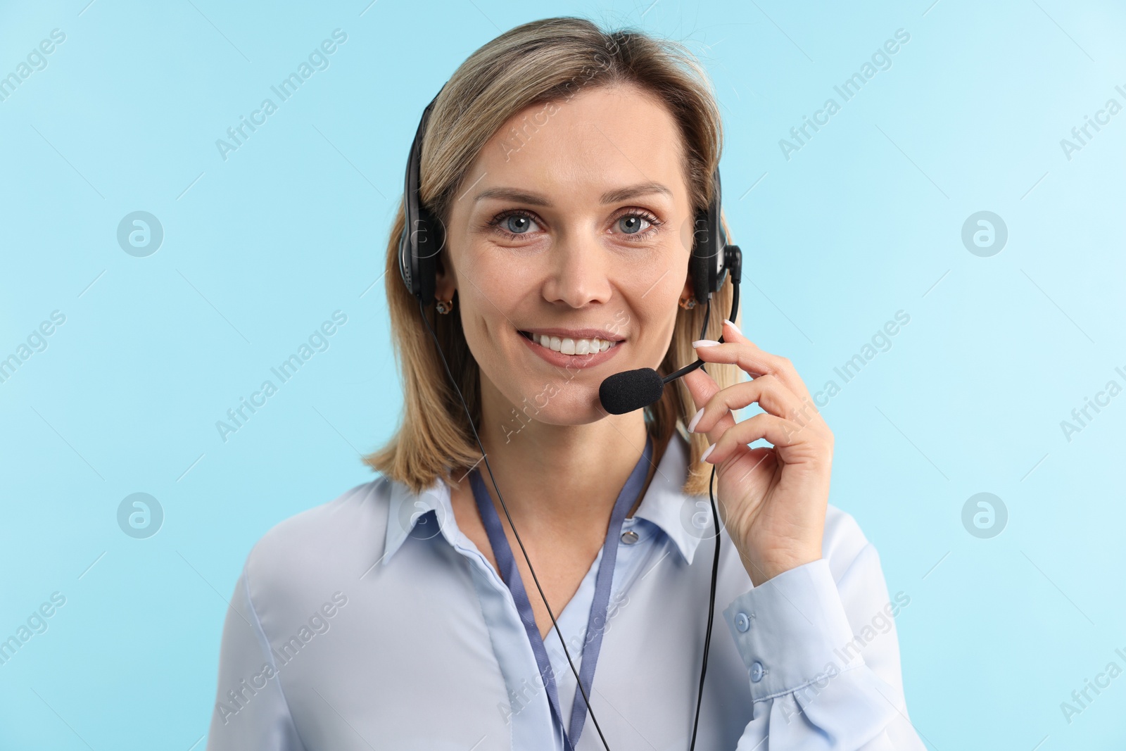 Photo of Technical support call center. Portrait of smiling operator on light blue background