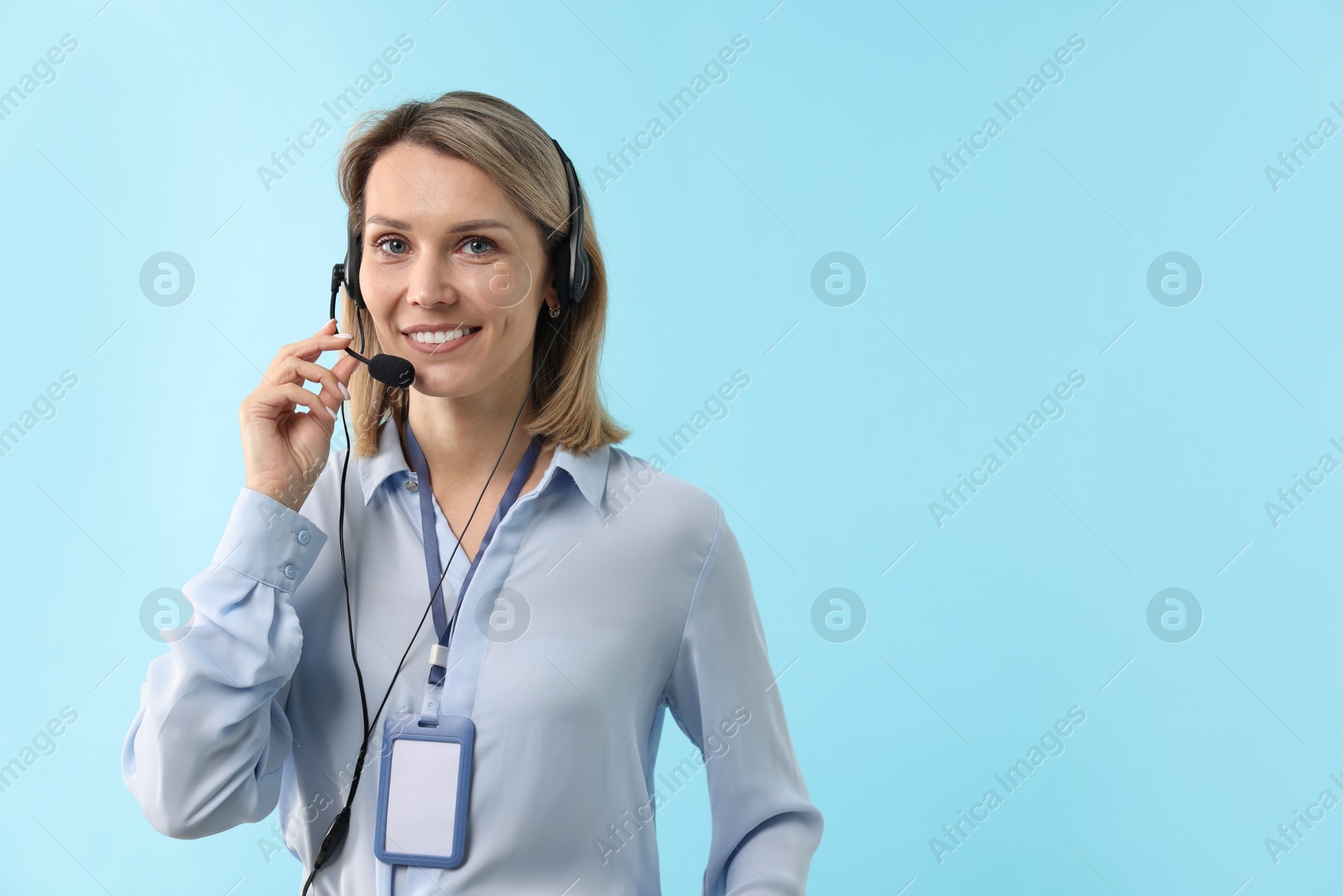 Photo of Technical support call center. Smiling operator on light blue background. Space for text