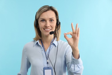 Photo of Technical support call center. Smiling operator showing ok gesture on light blue background