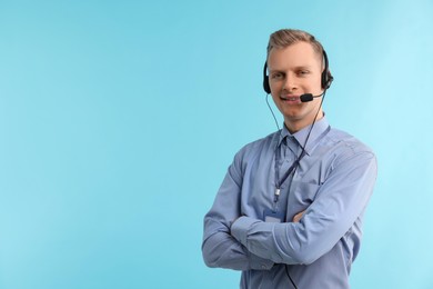 Photo of Technical support call center. Smiling operator with crossed arms on light blue background. Space for text