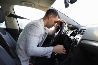 Tired driver sleeping on steering wheel in car