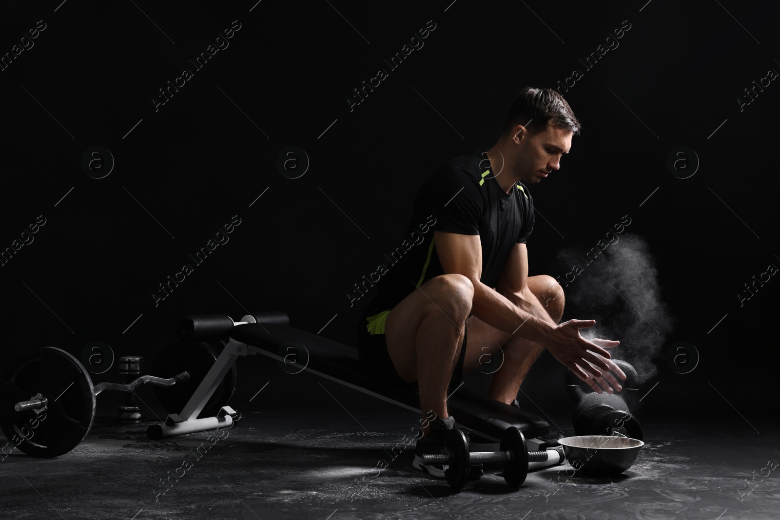 Photo of Man clapping hands with talcum powder before training on black background