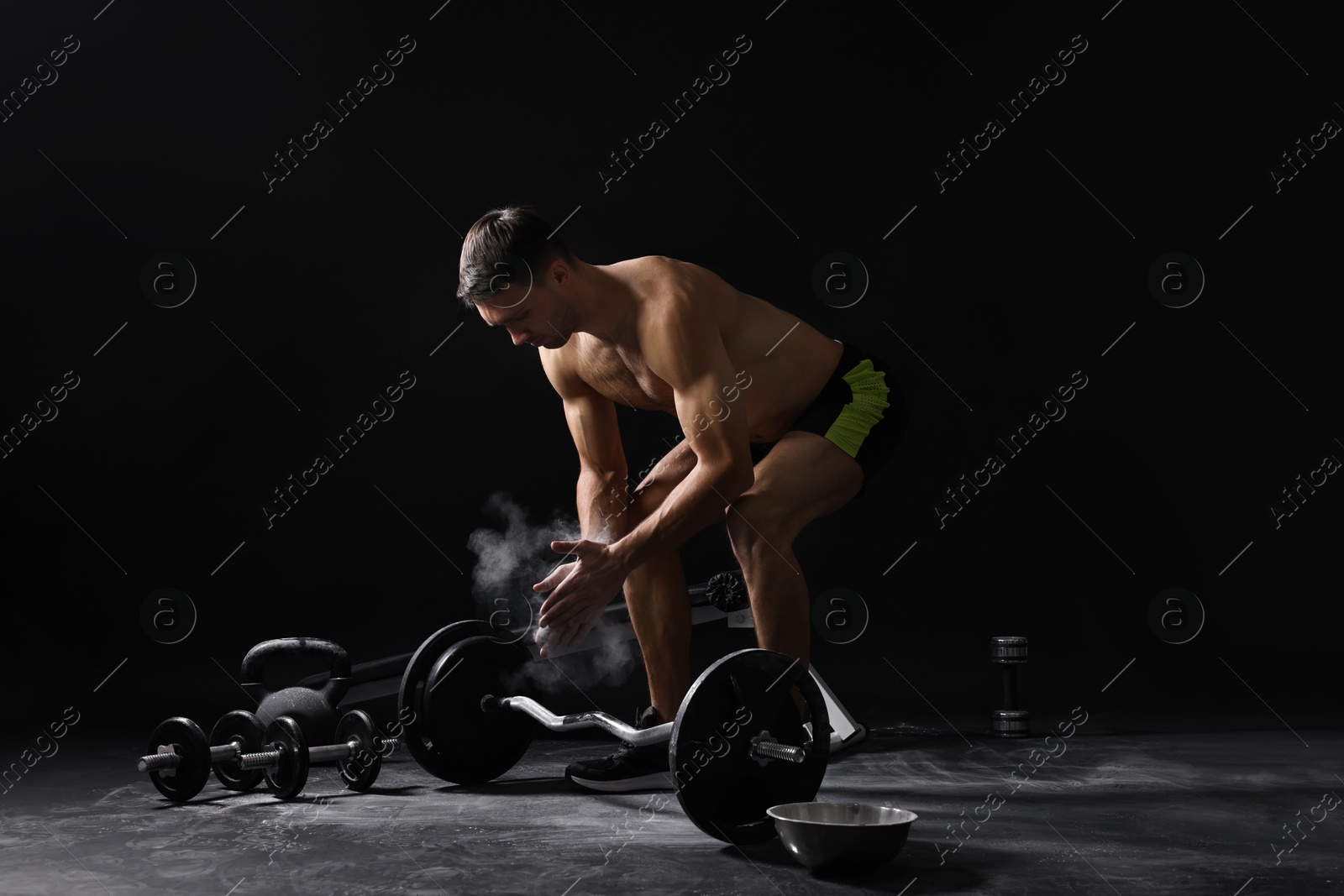 Photo of Man clapping hands with talcum powder before training on black background