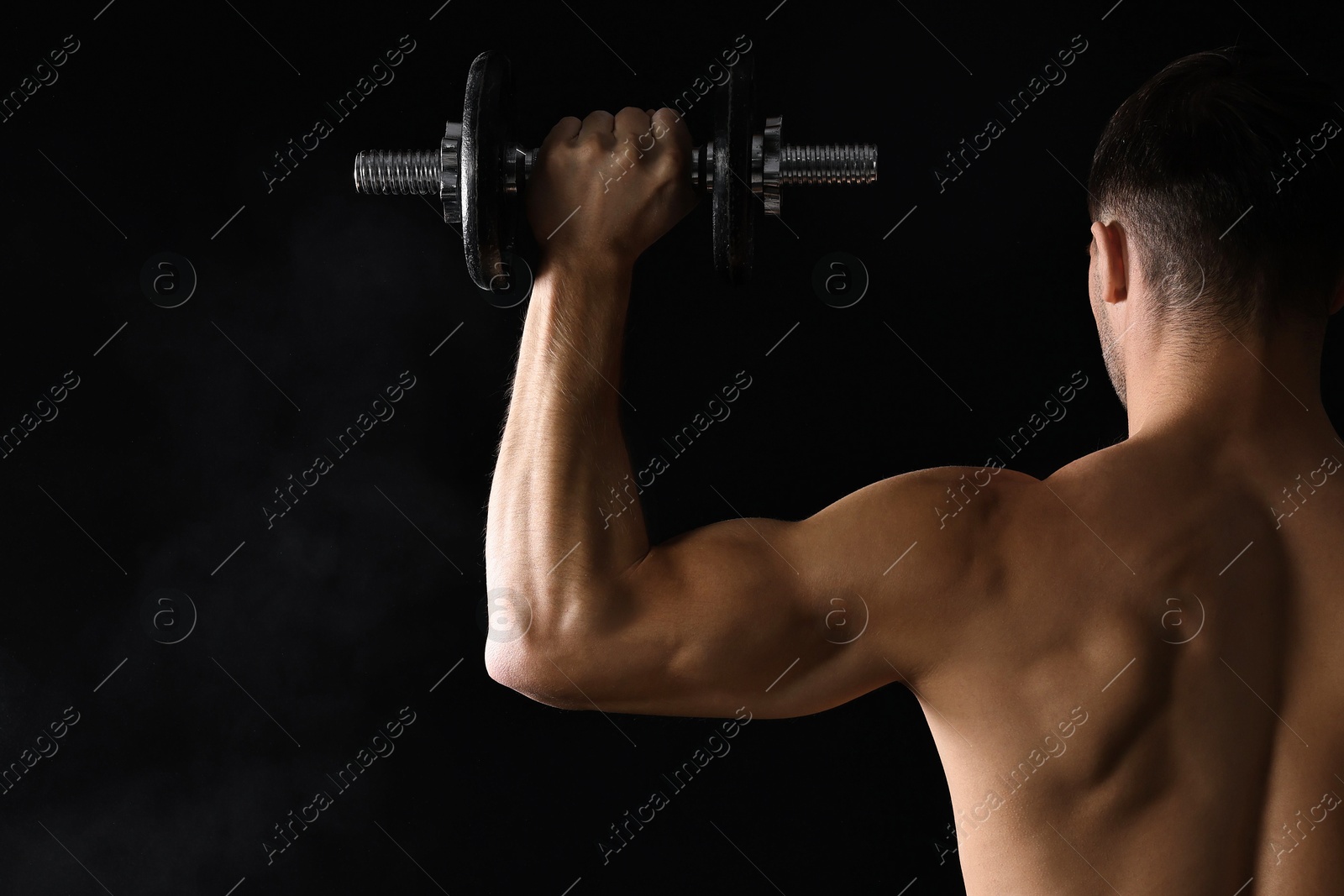 Photo of Man training with barbell on black background, back view