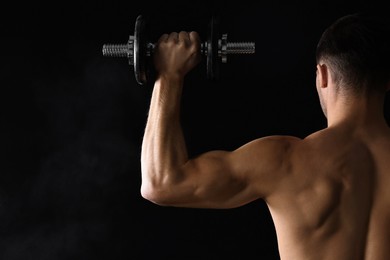 Photo of Man training with barbell on black background, back view